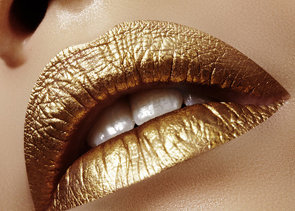 护肤品金色摄影照片_特写女性丰满的嘴唇与金色化妆。