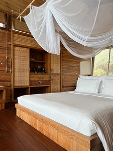 热带雨林山上带床、床上用品和照明装饰的室内木制热带度假村