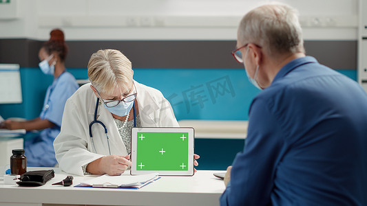 医生和退休人员在平板电脑上看绿屏