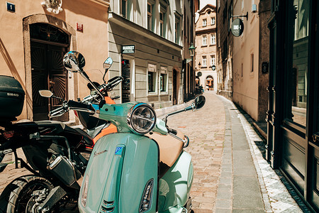 vespa摄影照片_捷克共和国布拉格 — 2022年7月。欧洲老街上的蓝绿松石色复古意大利 Vespa 摩托车。