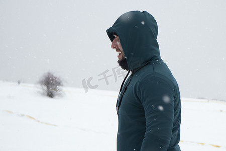 风景大片摄影照片_在白雪皑皑的地平线背景下穿着绿色运动插肩袖的帅哥。