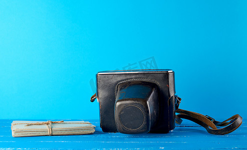 黑色皮箱摄影照片_蓝色背景中棕色皮箱中的旧胶片相机