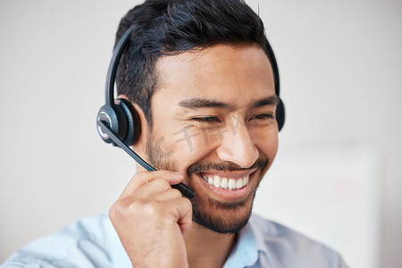 微笑的混合种族呼叫中心代理戴着耳机微笑的特写。