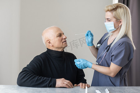 医护人员手部特写，将鼻拭子引入缓冲管，在家中从一位老人家中采集鼻腔培养物样本。 