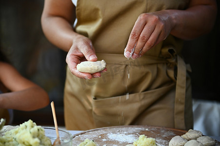 注意动效摄影照片_细节：家庭主妇的手在木板上撒面粉，同时动手包饺子，烹饪自制的 varenyky