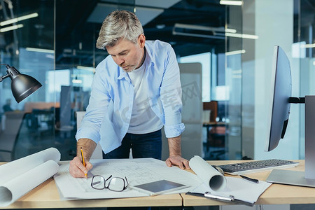 一位经验丰富的建筑师正在画图，一个人在现代办公室里对着电脑