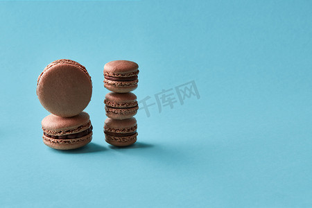 美食背景图案摄影照片_特写工作室拍摄的蓝色背景上的美味巧克力马卡龙。