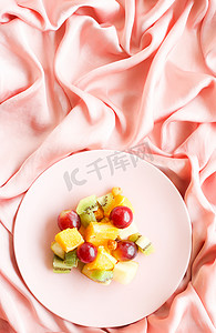 丝绸上的多汁水果沙拉，平铺-健康的生活方式和床上早餐概念