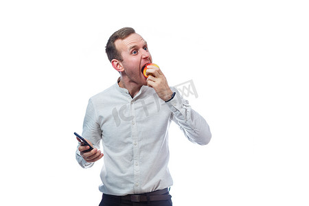 苹果手机黑色手机摄影照片_白人男性商人手持黑色手机，手里拿着一个红黄色的苹果。