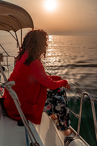 强风吹拂摄影照片_在阳光明媚的夏日，一位女士坐在游艇的船头，微风吹拂着她的头发，背景是美丽的大海