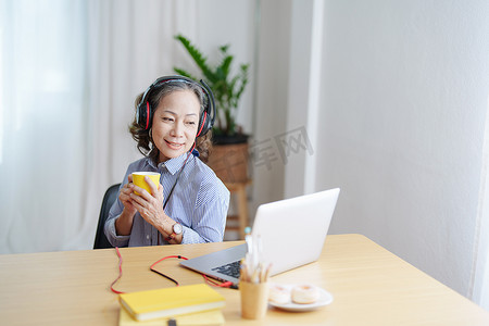 放松时间，一位老妇人的肖像快乐地听音乐，在电脑会议之间放松