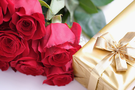 金色的缎带摄影照片_情人节礼盒，系着金色缎带蝴蝶结和美丽的玫瑰