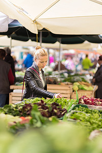 妇女在当地食品市场购买蔬菜。
