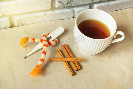 治疗感冒的概念 — 肉桂热茶、温度计和围巾