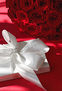 豪华假日丝绸礼盒和红色背景的玫瑰花束、浪漫惊喜和鲜花作为生日或情人节礼物