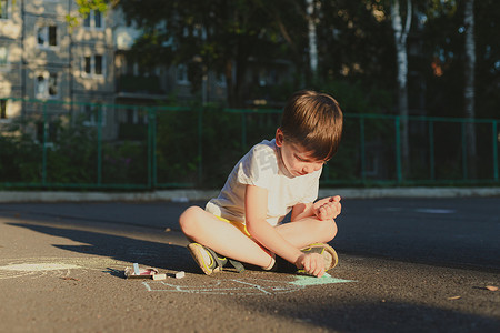 一个男孩用蜡笔在沥青上画出一种生活方式。
