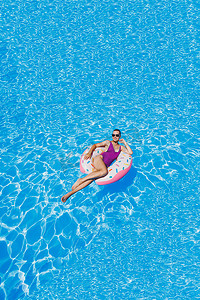 游泳池里戴着太阳镜的苗条女人穿着鲜艳的泳衣，戴着充气游泳圈，夏天的照片，游泳摄影，夏天的女人照片。