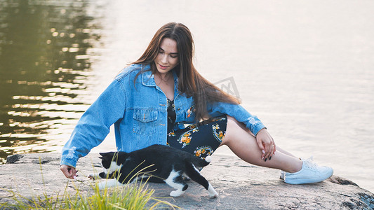 一个女孩和猫的摄影照片_一个女孩在湖边和一只猫玩耍。