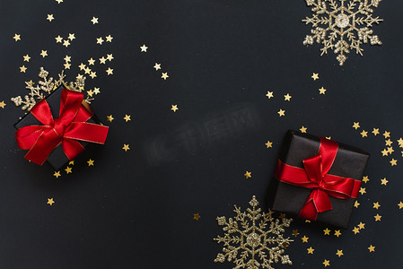 新年礼物，黑色背景上有红色蝴蝶结，上面有五彩纸屑、金色雪花和球。