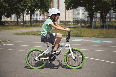 白人男孩，运动自行车手，穿着运动服和安全运动头盔在户外骑自行车。