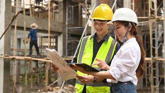 经理摄影照片_戴安全帽的工程师和经理建筑工人正在施工现场讨论计划细节