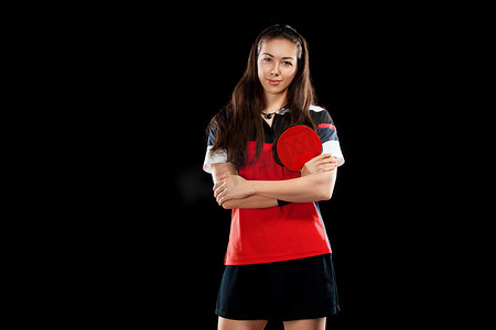 在黑色背景上孤立的年轻漂亮的运动型女孩玩家乒乓球。