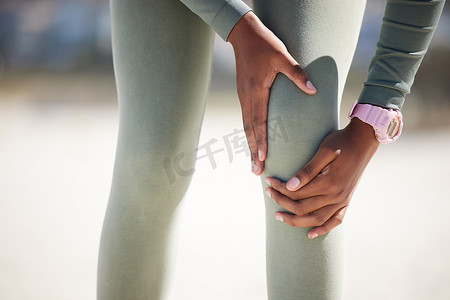 活跃的女人在户外锻炼时疼痛地抱着她的腿。
