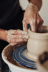 陶器手稿摄影照片_陶艺家在工作中的特写，陶艺大师在轮子上制作陶罐