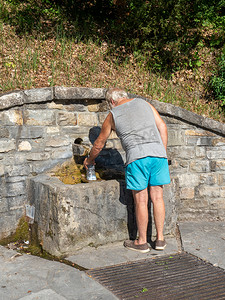 公共生活摄影照片_白种人老人在公共来源装瓶新鲜泉水