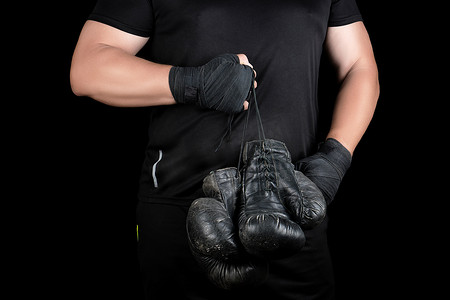 拳击黑摄影照片_穿黑衣服的运动员拿着非常旧的复古皮革黑 bo