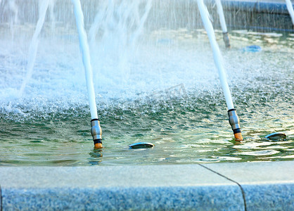 盛大开业开业大吉摄影照片_由抛光花岗岩制成的城市喷泉中，金属喷嘴喷出强大的水流。