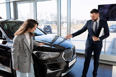 汽车经销店的一位年轻女性与经理一起选择一辆新车，汽车租赁概念