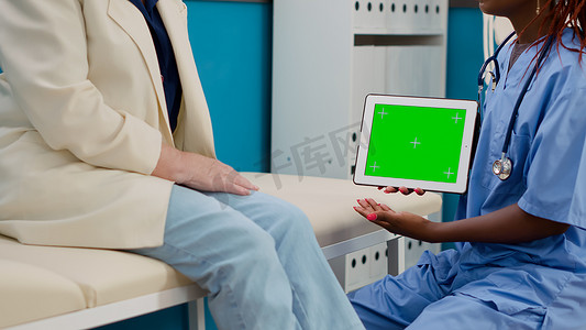 持有带绿屏显示的数字平板电脑的医疗助理