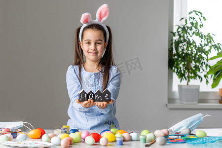 一个可爱的小女孩的肖像，穿着复活节兔子耳朵，手里拿着彩蛋。