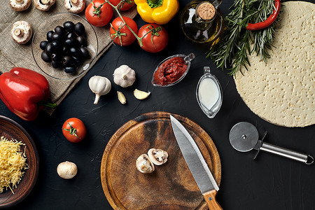 比萨原料摄影照片_用传统的比萨准备原料切割木板：奶酪、西红柿酱、蘑菇、橄榄油、胡椒、香料。