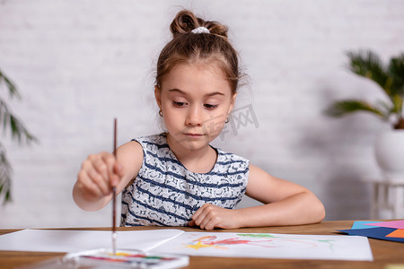 桌边受启发的小女孩用颜料画画