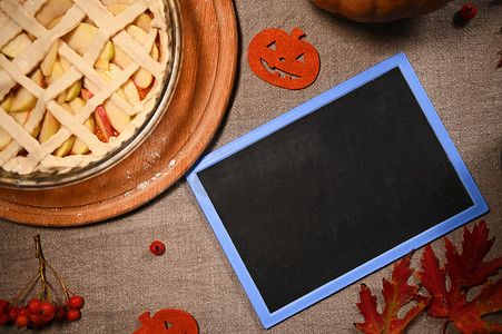 烤南瓜摄影照片_顶视图新鲜出炉的感恩节派，配有南瓜和苹果、脆皮格子和带复印空间的黑板