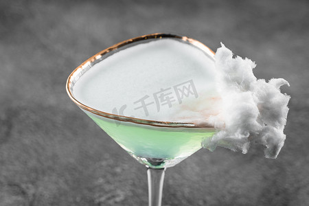 玻璃杯中的绿色酒精鸡尾酒装饰着灰色背景的棉花糖。