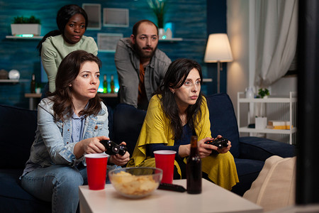 在线比赛期间坐在沙发上使用操纵杆玩电子游戏的集中女性
