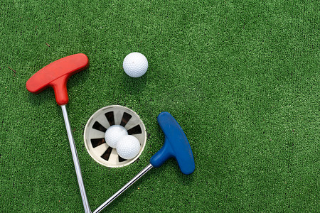 各种微型高尔夫球推杆和球在人造草坪上倾斜。
