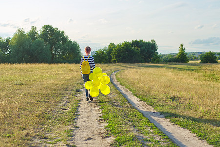背着背包和黄色气球在乡村道路上奔跑的少女，后视