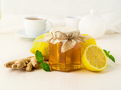 治疗感冒的流行方法 — 一罐蜂蜜、生姜、薄荷、白色背景的柠檬，侧视