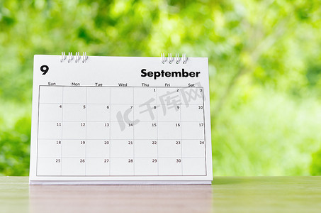 九月日历摄影照片_2022 年 9 月的日历桌，供组织者在自然背景的木桌上进行计划和提醒。