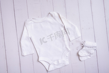 白色婴儿紧身衣模型，用于木质背景顶视图上的徽标、文字或设计