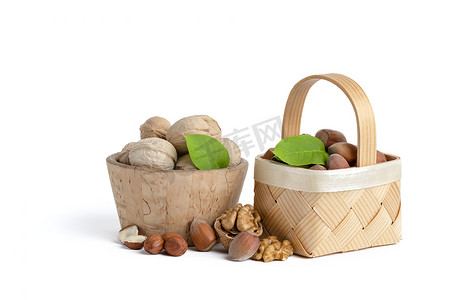 不同品种的核桃和榛子放在白色孤立背景的木碟和篮子里。