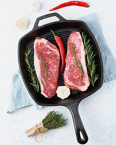 两块新鲜的生大整块肉、牛肉片、大理石西冷牛排放在铸铁大锅里。