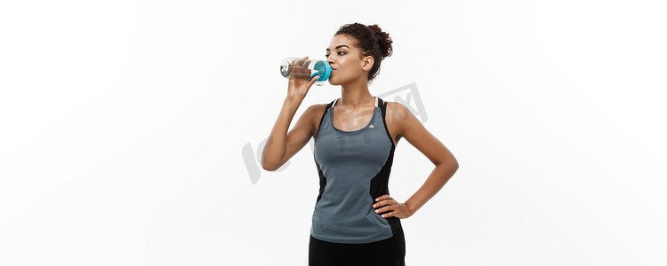 健康和健身概念-穿着运动服的美丽的非洲裔美国女孩锻炼后喝水。