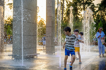 2021年1月摄影照片_乌克兰基辅 - 2021年8月1日：男孩在喷泉里跳跃。