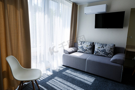 酒店房间内的大灰色沙发配有电视和大窗户