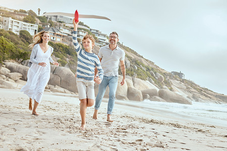 快乐的白人父母和孩子一起玩玩具飞机，同时在海滩上度过一个轻松有趣的家庭暑假，享受美好时光。